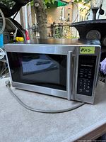 Front angled view of microwave showing stainless front, handle, keypad and overall condition