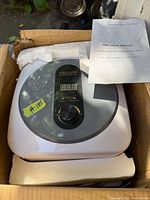 Top view of the Fisoceny mini water heater inside box with manual visible