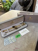 Both watches in open display case with outer box and warranty card visible