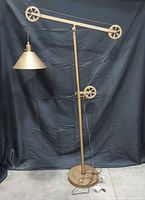 Full view of brass-tone adjustable floor lamp showing base, pole, pulley arm and shade