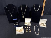 Overall lot showing three necklaces on busts and boxed jewelry pieces