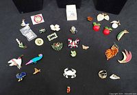 All enamel pins and miniature deck laid out on black cloth