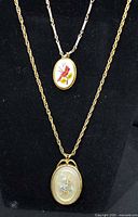 Both necklaces displayed: shorter bar-link chain with enameled cardinal pendant and longer rope chain with pressed flower pendant