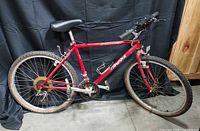 Full left-side view of red Specialized Hard Rock mountain bike showing overall condition, flat tires, missing kickstand