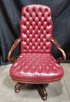 Front view of red leather tufted office chair with wood arms and base