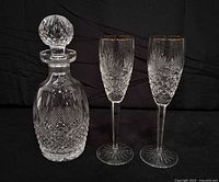 Decanter with stopper alongside two gold-rim wine glasses