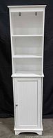 Full front view of white tall cabinet showing shelves and door