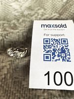 Sterling silver woven band ring beside auction tag