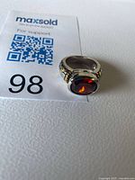 Ring beside lot tag showing red stone and band