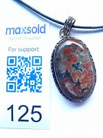 Front view of jasper pendant next to scale card