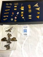 Display case with assorted gold-tone tie clips, tacks, pins, cufflinks; carded western button covers in foreground