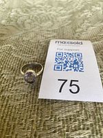 Ring lying flat beside lot card showing amethyst stone and band