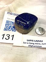 Front view of polished lapis lazuli next to coin for scale