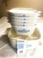 Stack showing four petite pans, two square casseroles and one clear glass lid