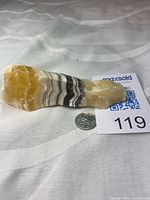 Full view of yellow calcite specimen beside coin for scale