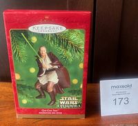 Front of red Hallmark Keepsake box showing image of Qui-Gon Jinn ornament and Star Wars Episode I logo
