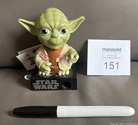 Front view of Yoda candy dispenser with pen for scale