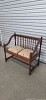 Full view of wooden spindle-back bench with two seat cushions