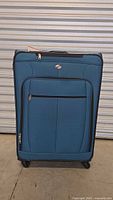 Front view of blue American Tourister AT Pop Plus suitcase standing upright