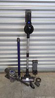 Dyson motor body, purple wand, unbranded stick vacuum assembled, accessories on floor