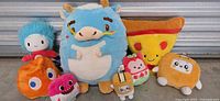 Group shot of all plush toys and pizza slice pillow