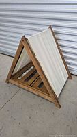 Full view of wooden A-frame pet house showing canvas panel and slatted base