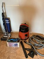 Overall lot showing Sanitaire upright, Fein canister, hose, wand, and box of accessories
