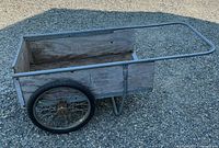 Left side view of wooden cart showing metal handle, wheel, and side panel