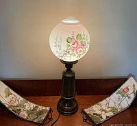 Full view of lamp illuminated with both needlework hangings beside it
