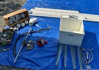 Overall lot on blue tarp showing pipes, sink, fittings, threader, pump