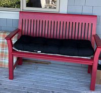 Red bench with black tufted cushion on seat