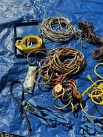 Assorted ropes, straps, pulley blocks displayed on blue tarp