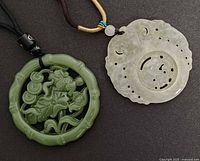 front view of two jadeite pendants showing color and carvings