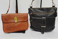 Brown and black Roots leather crossbody bags side by side