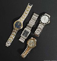 All four watches laid flat on black background