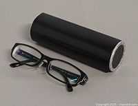 Eyeglasses beside cylindrical case showing overall items