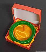 Bracelet resting in orange presentation box with yellow satin lining