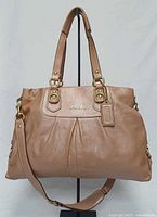Front view of Coach Ashley copper metallic leather carryall showing logo, pleating, dual handles, shoulder strap and hangtag