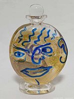 Front view showing blue face motif, stopper, pedestal base