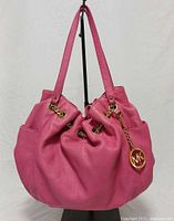 Front view of pink Michael Kors Fulton hobo handbag showing gold hardware and MK charm