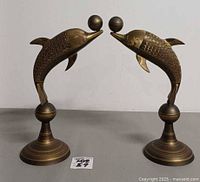 Front view of both brass dolphin sculptures