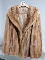 Front view of golden brown mink fur coat on hanger