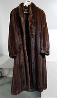Front view of full-length brown otter fur coat on hanger