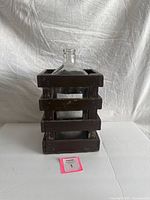 Front view of glass demijohn inside wood crate