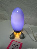 Front view lit, showing blue/white glow, feet base, cord