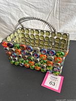 Front view showing multicolor bottle-cap lattice and coiled handles