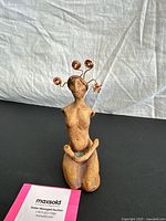 Full view of ceramic kneeling female figurine with copper wire hair