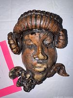 Front view of ceramic goddess face wall hanging showing facial details and glaze
