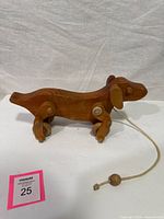 Profile view of wooden dog pull toy showing wheels and pull cord