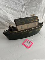 Overall view of handmade wooden boat model showing hull, cabin, bird and captain figures